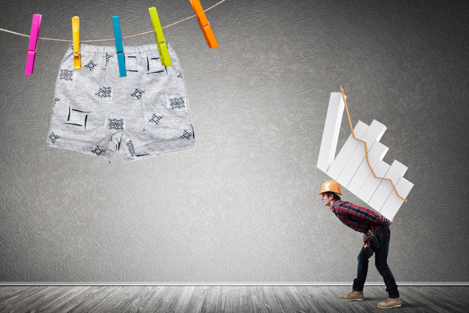 A builder carrying a heavy bar chart showing an upward trend. In the top left hand corner of the page is a pair of boxer shorts on a washing line.