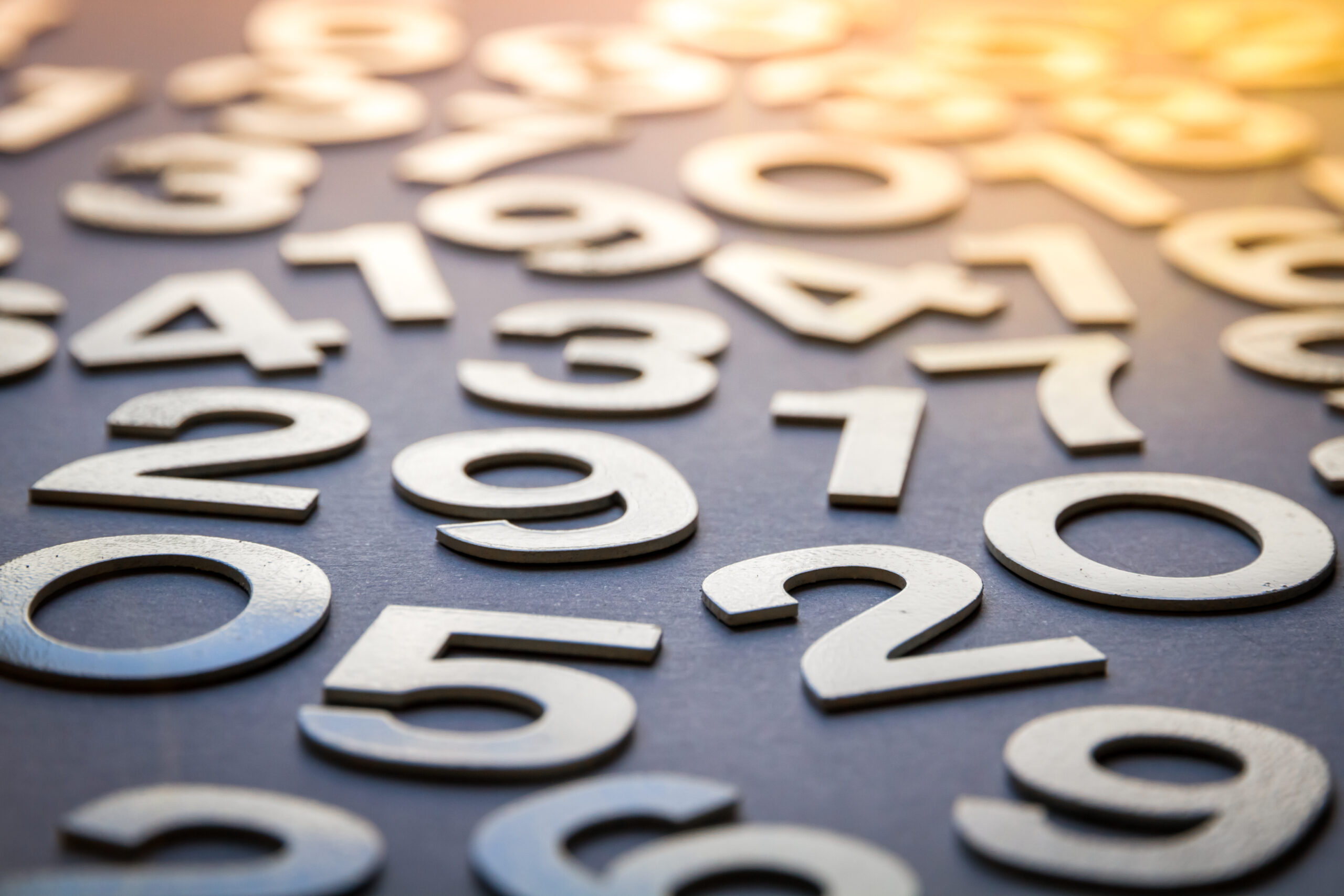 Grey base with numbers laid on top in a lighter colour. In the foreground the numbers are clear - in the background they are blurred and there is an orange glow.